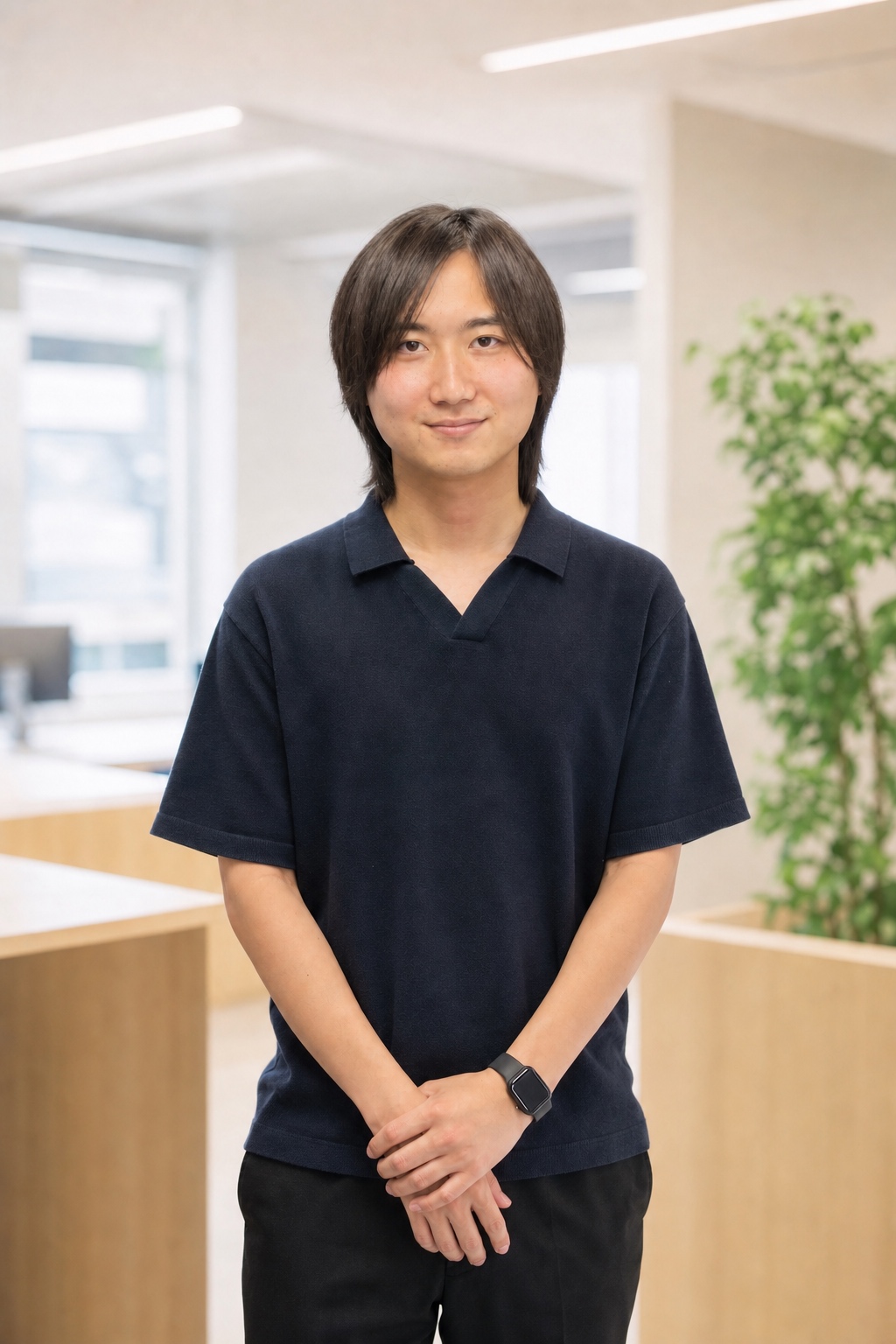 ネイビーのニットポロを着て正面を向くWE株式会社メンバー M.O.